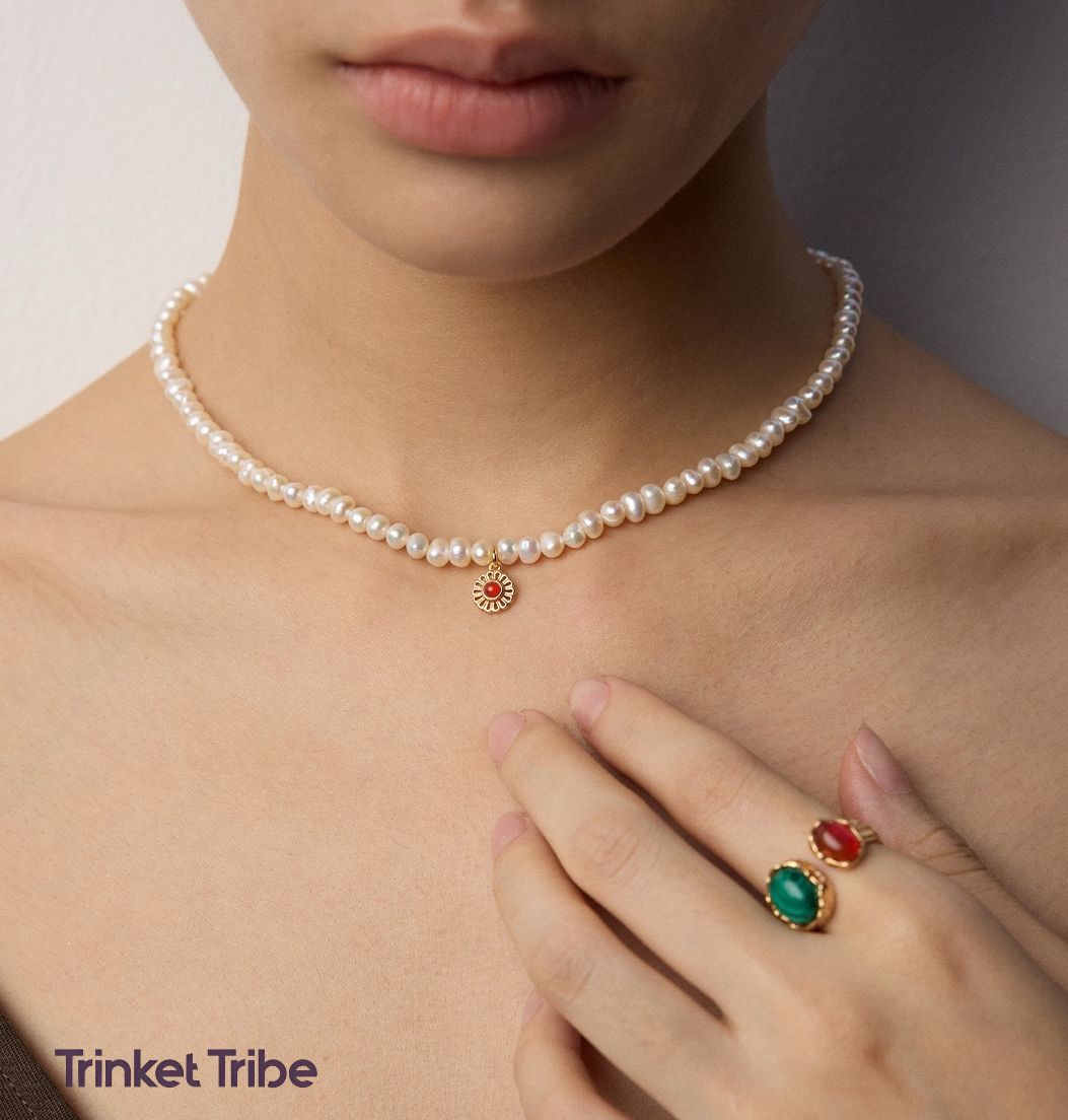 Elegant freshwater pearl choker necklace with gold sunburst charm and red gemstone, paired with adjustable gold-plated ring featuring green and red gemstone  – handcrafted jewelry by Trinket Tribe