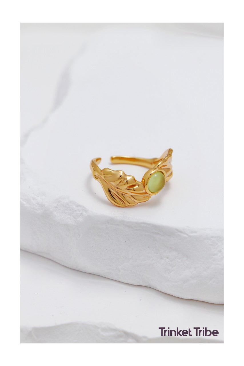 Elegant gold leaf ring with green gemstone centerpiece, adjustable nature-inspired jewelry on minimalist white background – perfect for boho, cottagecore, and earthy fashion styles.