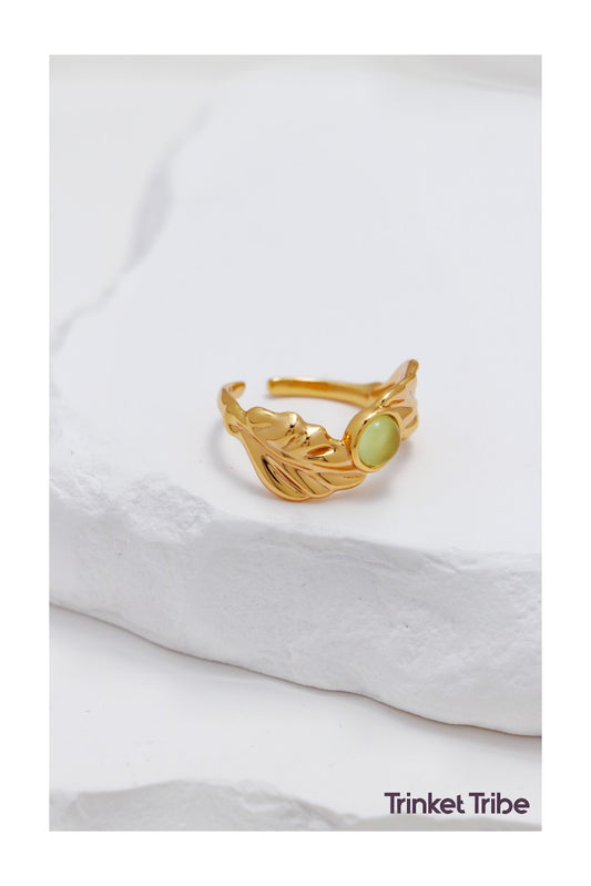 Elegant gold leaf ring with green gemstone centerpiece, adjustable nature-inspired jewelry on minimalist white background – perfect for boho, cottagecore, and earthy fashion styles.
