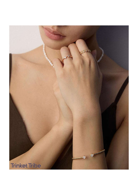 This jewelry set includes a gold-toned open bangle and ring with a twisted design. Each end is set with a square-cut stone for a touch of sparkle. The style is simple, modern, and elegant—perfect for both everyday use and special occasions.